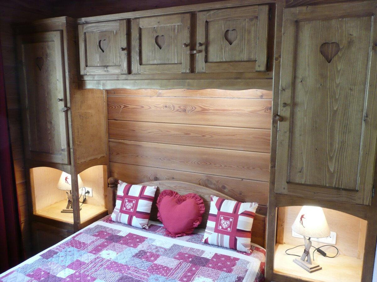 Chambre du chalet La Datcha avec lit double et boiseries savoyardes à cœurs