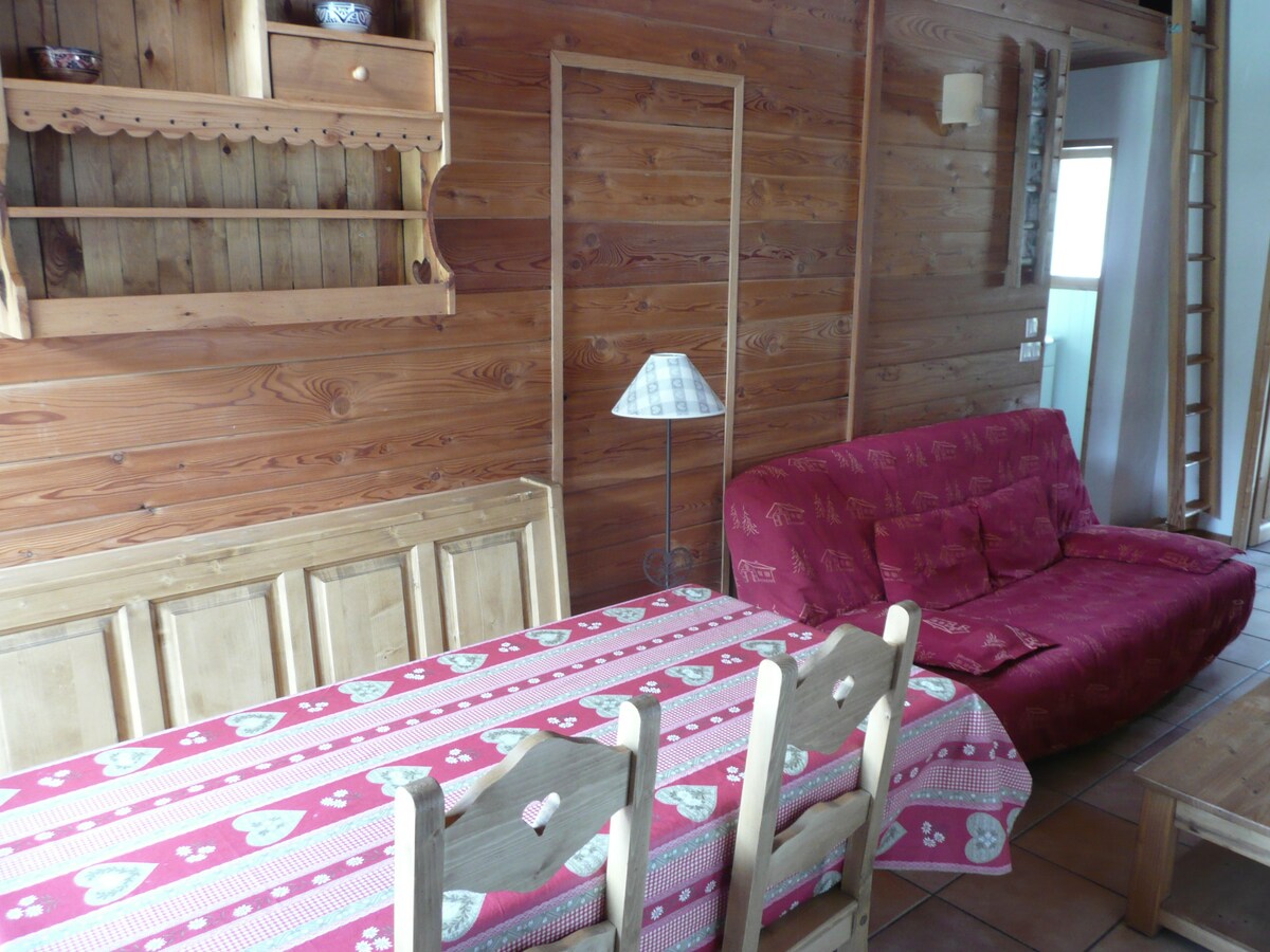 Coin repas en bois du chalet La Datcha avec nappe savoyarde et canapé rouge